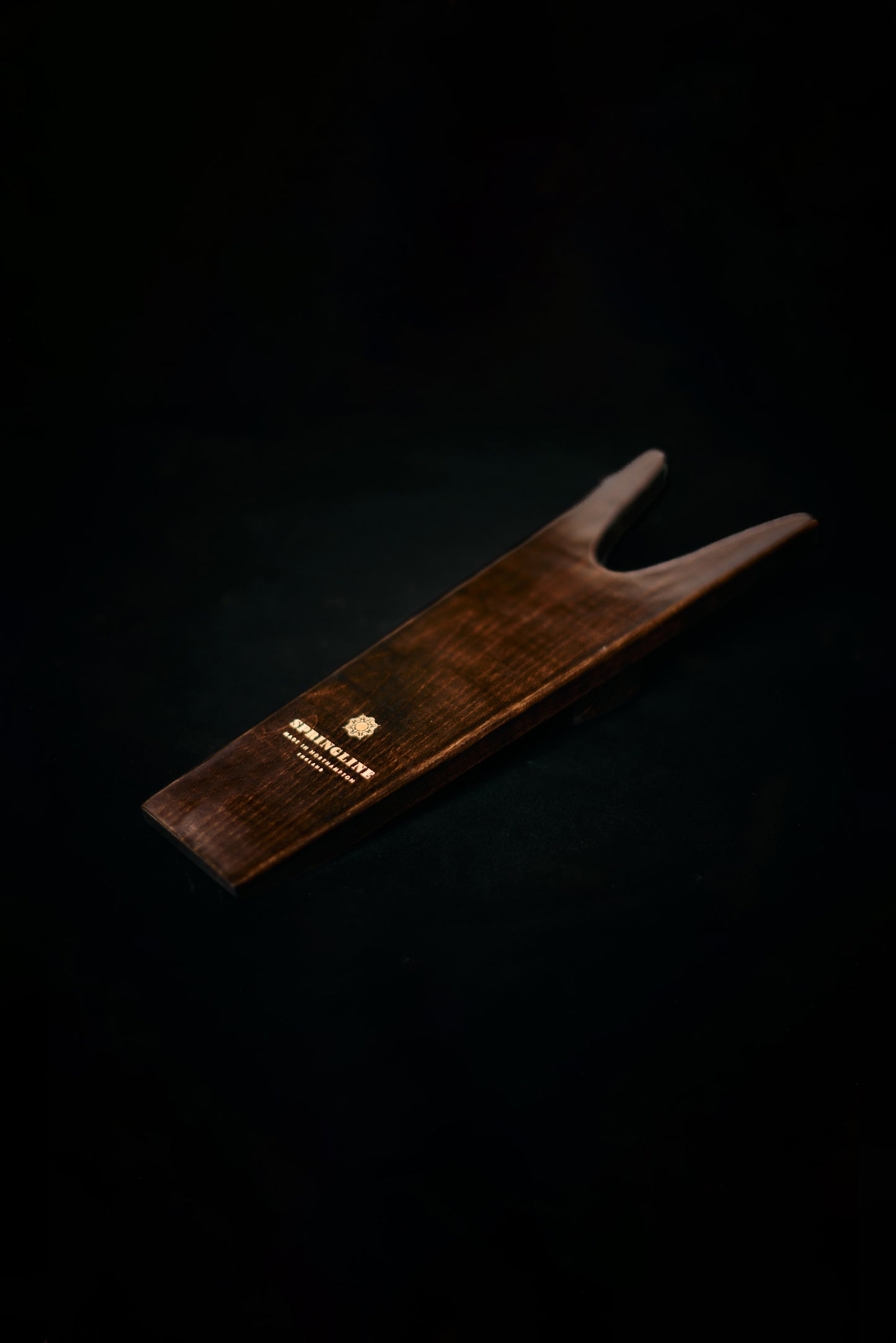 Wooden boot jack with a brand logo on a black background