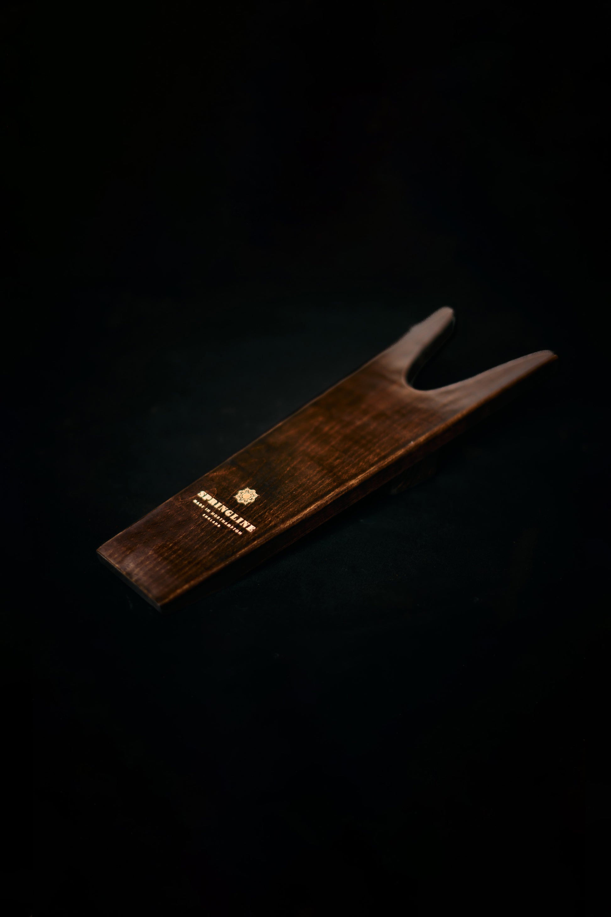 Wooden boot jack with a brand logo on a black background