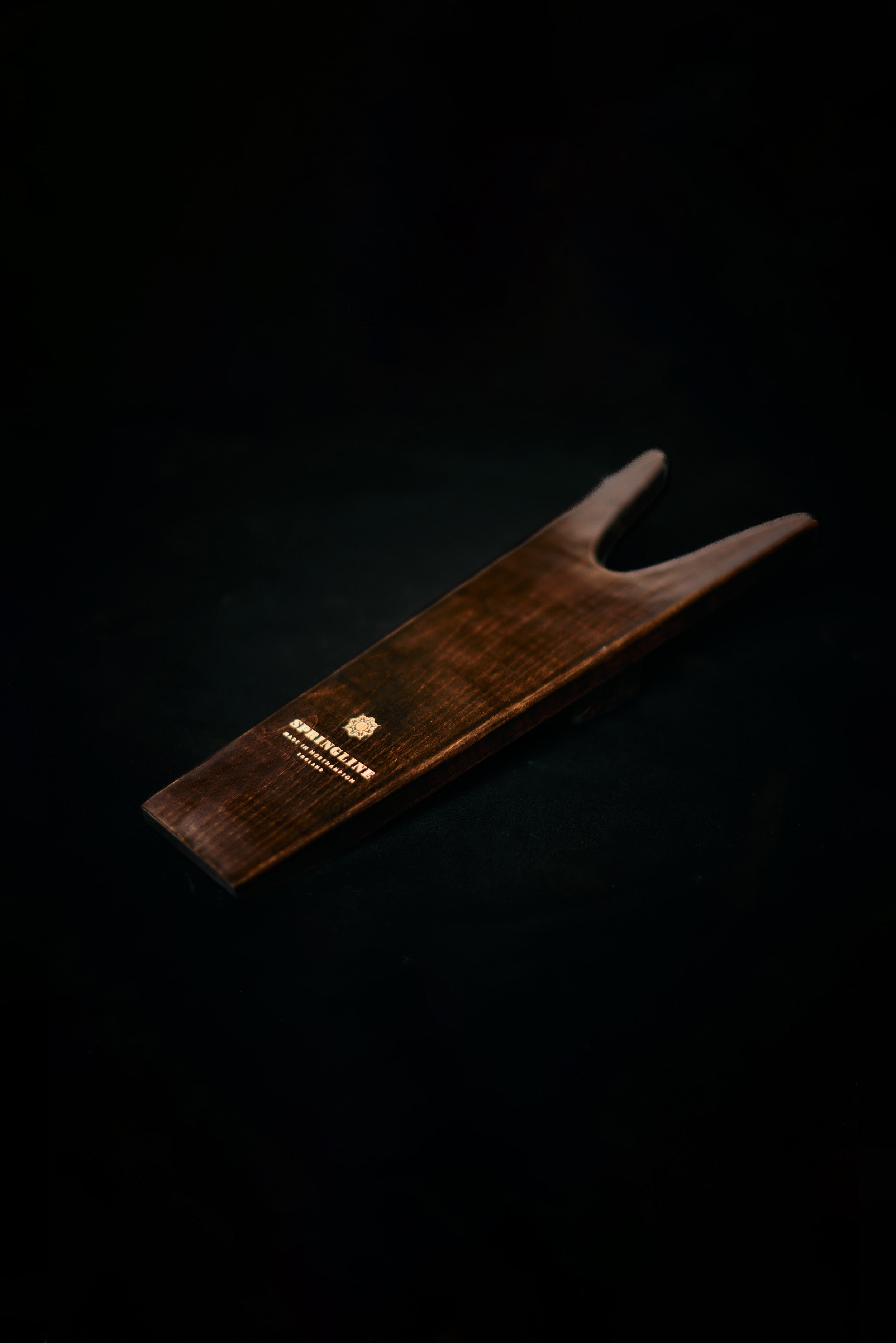 Wooden boot jack with a brand logo on a black background