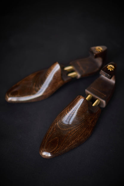 Wooden shoe trees with gold accents on a dark background