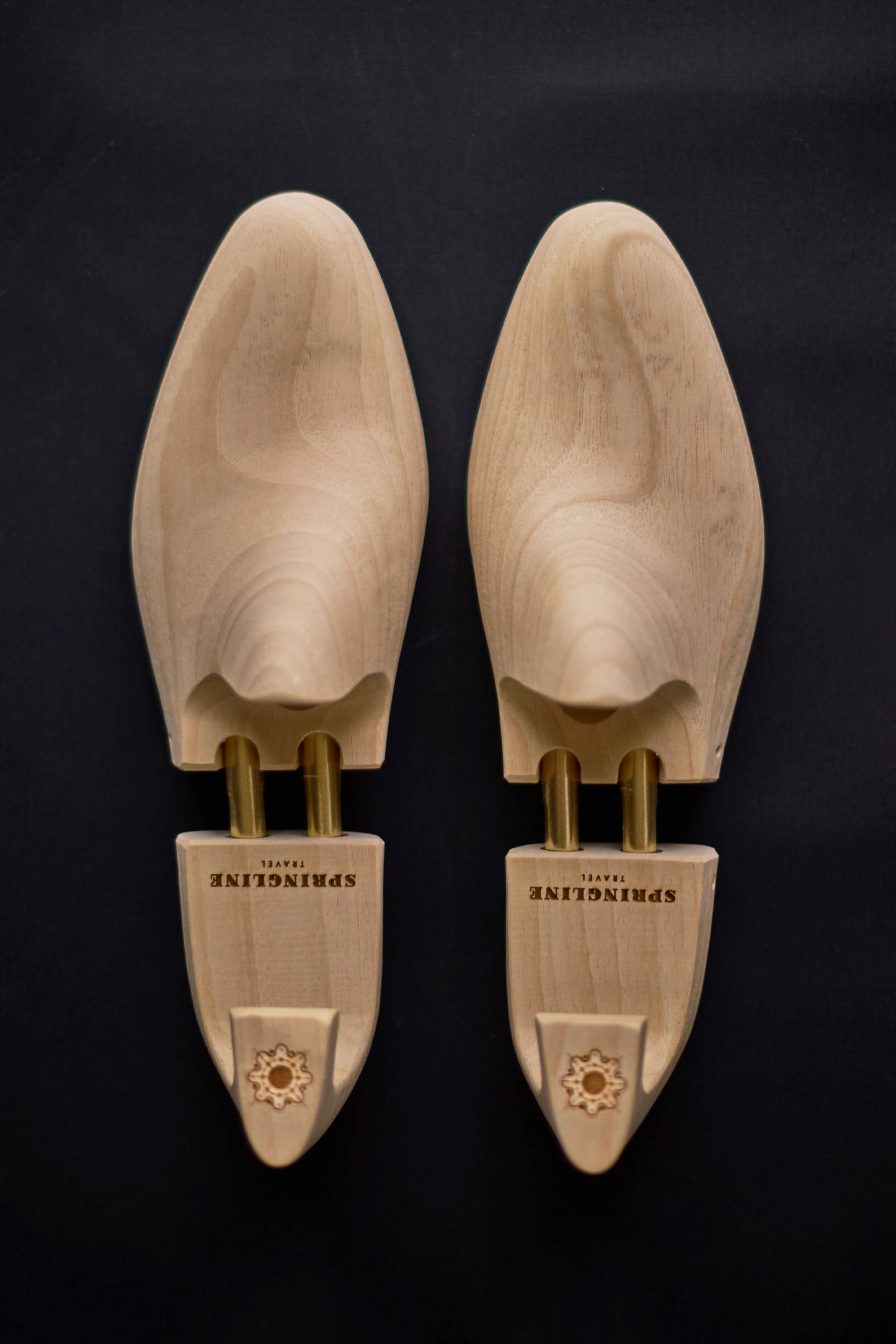 A pair of natural wooden shoe trees with the brand name 'Springline' inscribed on the side.