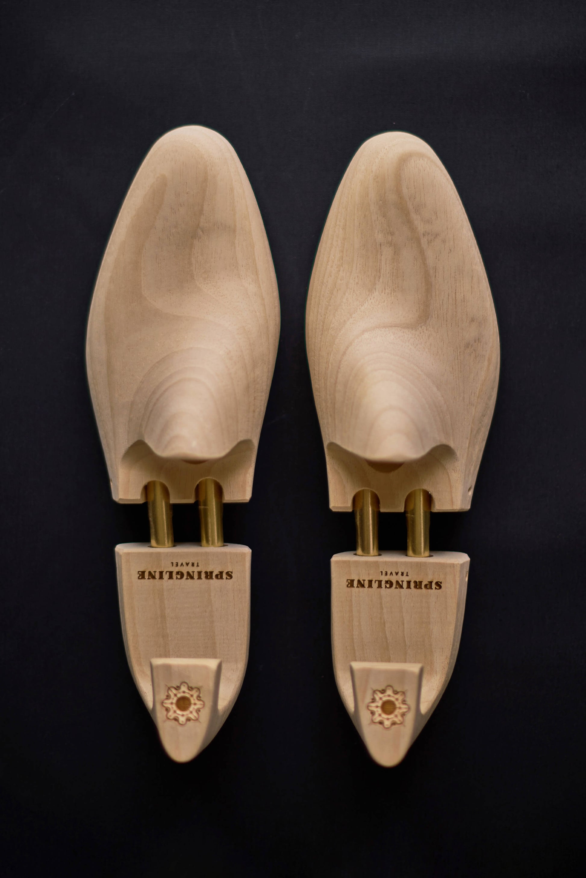 A pair of natural wooden shoe trees with the brand name 'Springline' inscribed on the side.
