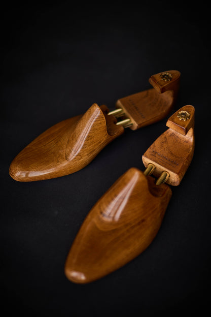 Pair of wooden shoe trees on a dark background